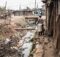 People walking along an open sewer in a slum in Africa